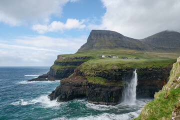 Fototapeta na wymiar Gásadalur located on the west side of Vágar, Faroe Islands. The village sits high and with a sheer drop where the waterfall Múlafossur plunges into the ocean.