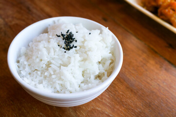 Rice in white cup on wood background and black sesame