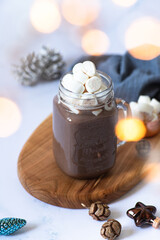 Cocoa drink with marshmallows in a glass mug, served on a light marble table with Christmas festive decorations. Winter mood. Close-up. Selective focus