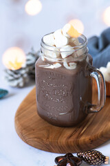 Cocoa drink with marshmallows in a glass mug, served on a light marble table with Christmas festive decorations. Winter mood. Close-up. Selective focus