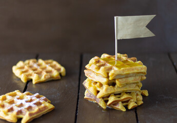 Carrot waffles with honey on a brown wooden background.