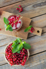 Glass of red currant cocktail or mocktail, refreshing summer drink with crushed ice and sparkling water on a wooden background.