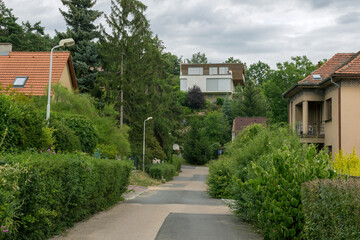 Fototapeta na wymiar Small street between houses and trees in a European village