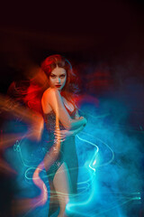 Young beautiful brunette woman in motion. Red blue color mixed light. Attractive girl in shiny...
