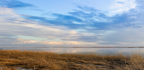 Fototapeta premium Sunset of a spring beach on the sea with the sky in yellow and blue shades.