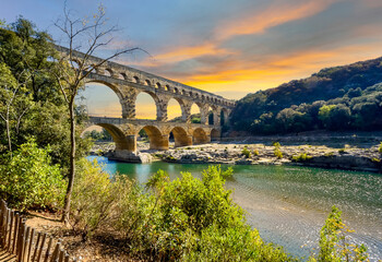 Sunset above the Gardon River in Provence, France with the ancient Roman aqueduct Pont du Gard in the view