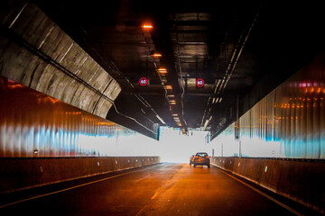 The light at the end of the tunnel - Cars nearing the end of a long tunnel with light reflecting...