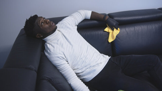 Exhausted african american black man resting on the couch after cleaning appartment. High quality photo