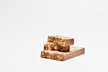 a small pile of tempting chocolate and almonds nougat on a light background