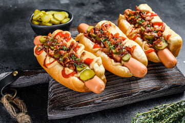 Hot dogs with different toppings. Dark wooden background. Top view