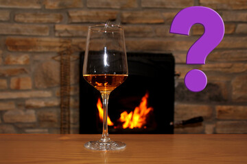 in front of the fireplace, in which firewood burns with a bright flame, there is one glass of wine, a question mark