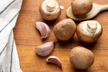 Aerial view of portobello mushrooms, garlic and kitchen towel, with selective focus, on wooden table, horizontal