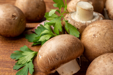 Close-up of portobello mushrooms, garlic and parsley, with selective focus, on wooden board, horizontal