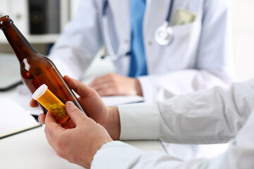Alcoholic hold in hand empty bottle at doctor reception office closeup. Grief and despair,...