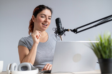 A charming woman radio host is broadcasting live on a laptop. Online radio concept