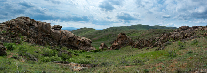 Red stone rocks and hills with bizarre shapes. Panoramic image. Spring. Almaty region, Kazakhstan.