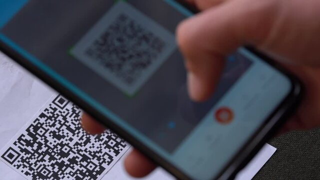Scanning a QR code And Contactless Payments during Covid-19 Pandemic. A man scans the QR code displayed by the merchant with their phone to pay for service