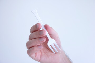 White plastic disposable fork modeled by Caucasian male hand isolated on white
