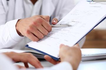 Male doctor hand hold silver pen and showing pad. Physical agreement form signature, disease prevention, ward round reception, consent contract sign, prescribe remedy, healthy lifestyle concept