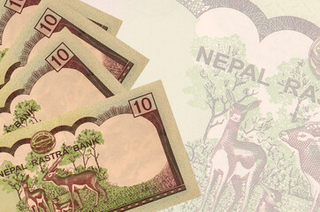 10 Nepalese rupees bills lies in stack on background of big semi-transparent banknote. Abstract business background