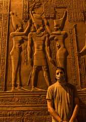 A young man with a face mask visiting at night the beautiful temple of Kom Ombo, the temple dedicated to the gods Sobek and Horus. In the town of Kom Ombo near Aswer, Egypt. Traveling in the covid-19 