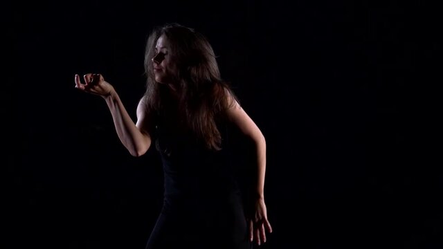young graceful lady is dancing in darkness, contemporary dance performance, medium shot