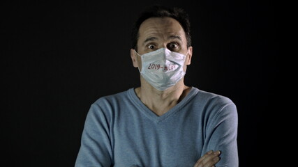 Middle-aged man in protective medical mask with inscription 2019-nCoV nervously breathing....