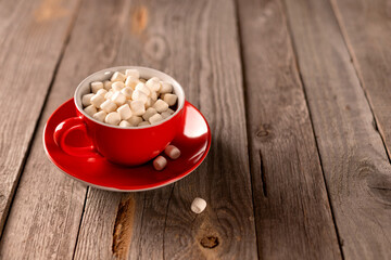 Hot chocolate with marshmallow in red cup on wooden table