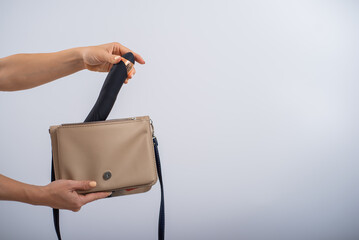 A woman puts a dildo in a handbag on a white background. Close-up of female hands with a black...
