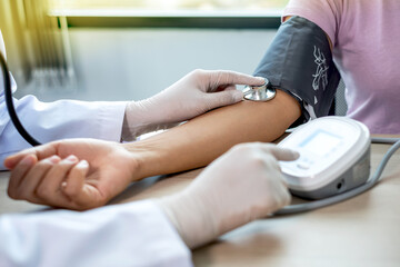 Fototapeta premium Doctor evaluates the patient with a stethoscope, blood pressure monitor and records the results, health medical checkup concept