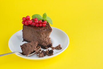 Closeup on piece of chocolate cheesecake on the white plate on the yellow background