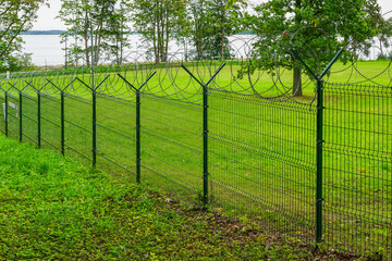 a metal fence of a military object with barbed wire