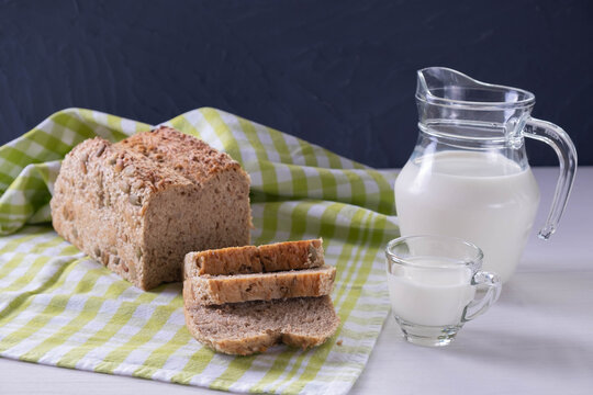 on the table a taon the table a tablecloth with freshly sliced bread, a jug and a mug of milk