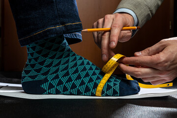 Shoe maker measures the feet of a client to create the perfect pair of classic shoes on a custom...