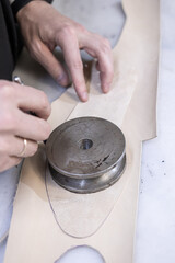 a master cutter cuts blanks from smooth light leather for a future pair of soft shoes