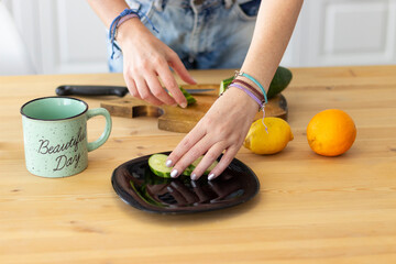 Girl's hands prepares in the kitchen. Cuts fruits on a cutting board near delicious fruits