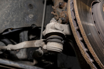 The end of the tie rod ends with a rubber connector, the brake disc is visible.