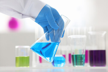 A male chemist holds test tube of glass in his hand overflows a liquid solution of potassium...