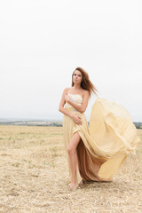 Fototapeta na wymiar woman walking in golden dried grass field. Natural portrait beauty. Beautiful girl in a wheat field