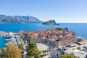 Aerial view of the peninsula on the Adriatic coast. On the peninsula there is an old town with a church, red roofs of houses and a berth with white yachts are visible - obrazy, fototapety, plakaty