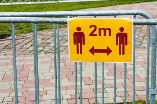 a metal barrier with a pictogram for observing a distance of two meters