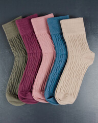 different colored women's socks on a dark wooden background. Lot of socks.