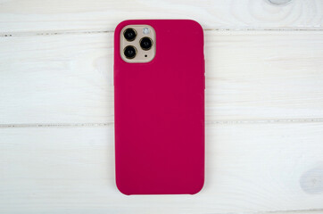 purple case for a smartphone on a white wooden background. View from above.
