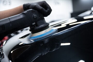 Car detailing studio worker renovating and polishing car paint