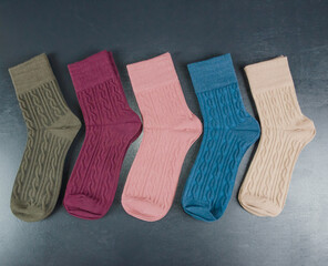 different colored women's socks on a dark wooden background. Lot of socks.
