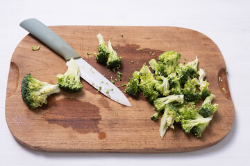 sliced broccoli and a knife on a wooden board
