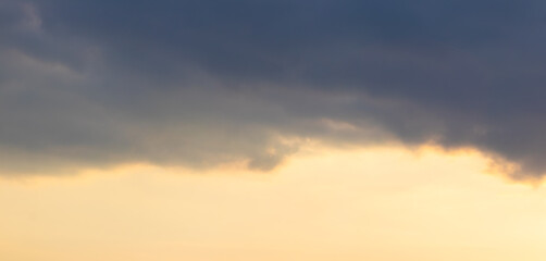 Dark cloud in the bright sky at sunset