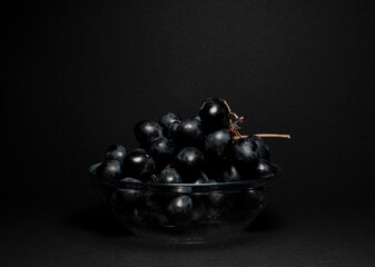 Juicy grapes on a black background in a plate