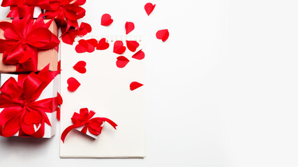 Valentine day composition : many gift boxes with red bows and a notebook on a white background with hearts. Top View.