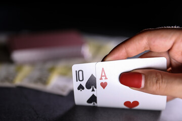 Close up of a woman hand holding  playing cards in a dark table. Online gambling. Addiction. Falling playing cards and poker chips	